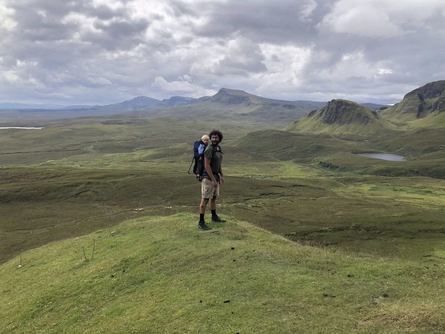 Yuri wandelt met zijn kind in een draagzak door de heuvels van Isle of Skye